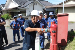 消防団の指導で消火栓にホースを接続する区民（芝生田区）